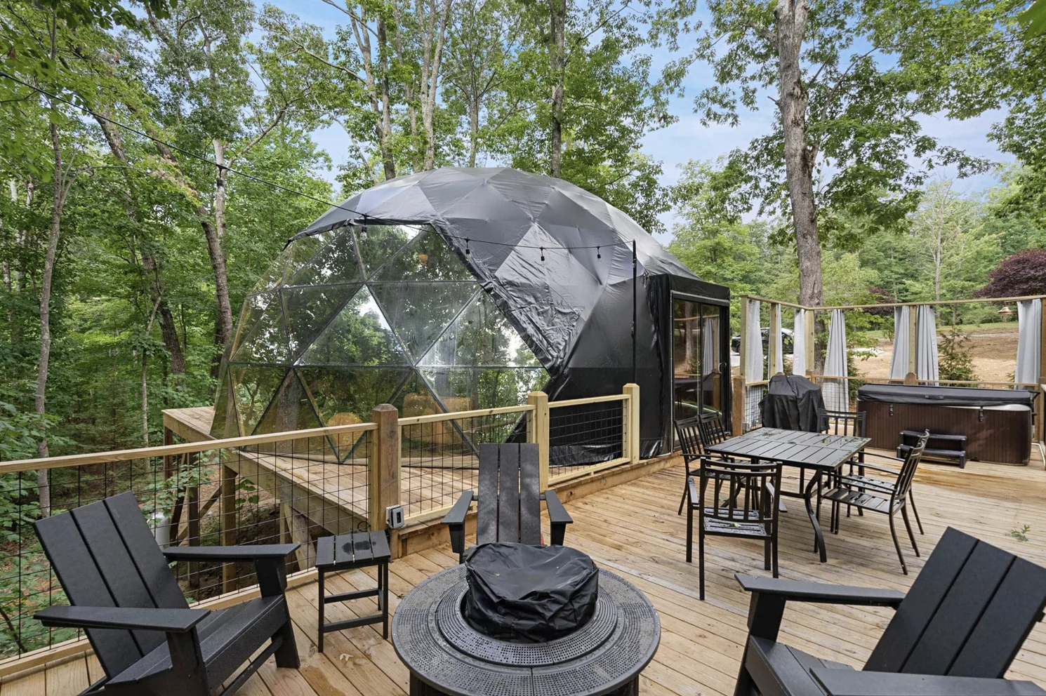 A deck beside a geodesic dome among trees.