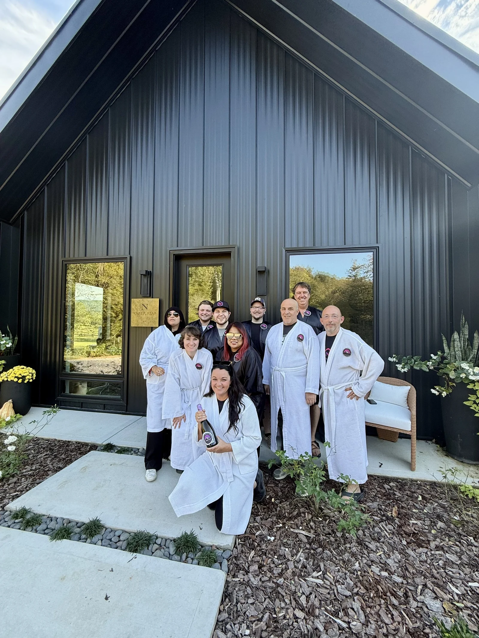 A group in spa robes gathered outside a cabin.